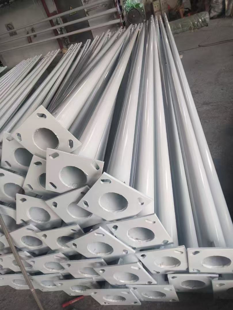 Finished powder-coated solar street light poles with base flange plates at WILSOLAR pole workshop in Zhongshan